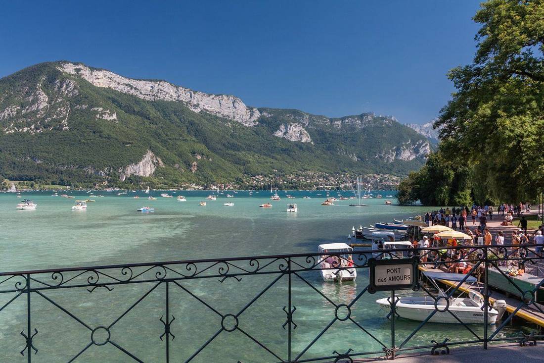 Le lac d'Annecy vu depuis le Pont des Amours, avec les pédalos amarrés et les montagnes en face