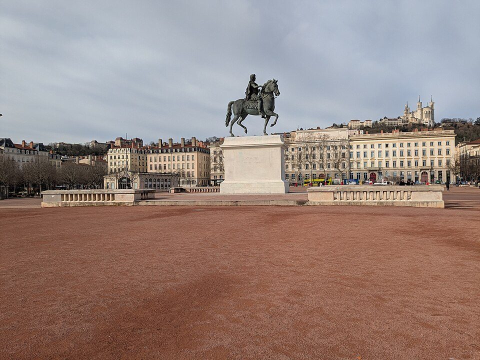 La place Bellecour, son sol de gravier ocre, la statue équestre de Louis XIV et la colline de Fourvière au fond