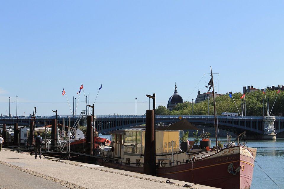 Une péniche amarrée sur les berges du Rhône, avec le dôme de l'Hôtel-Dieu en arrière-plan