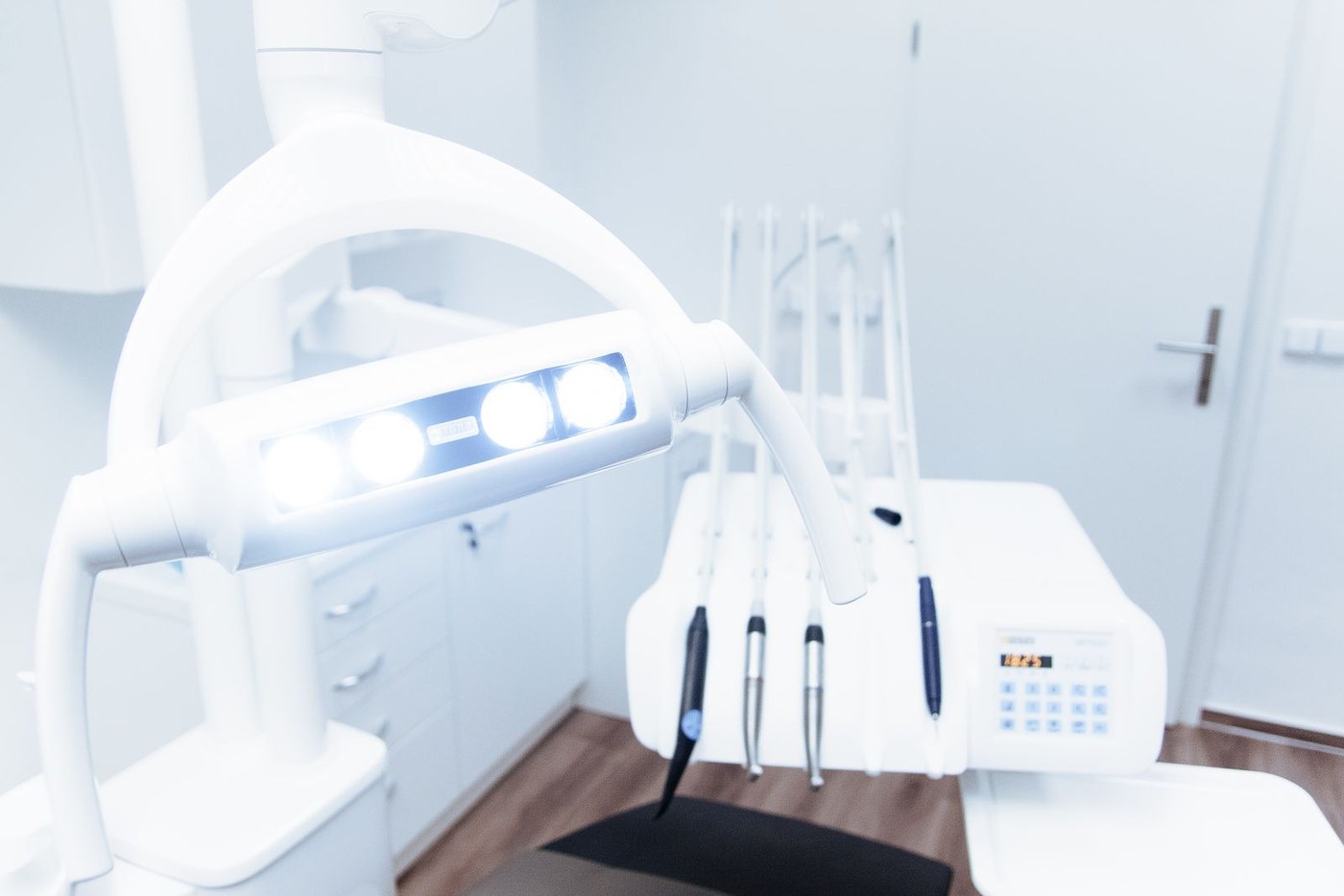 Fauteuil de cabinet dentaire vu de près : le scialytique allumé et le cordon d'instruments suspendu au-dessus du plan de travail