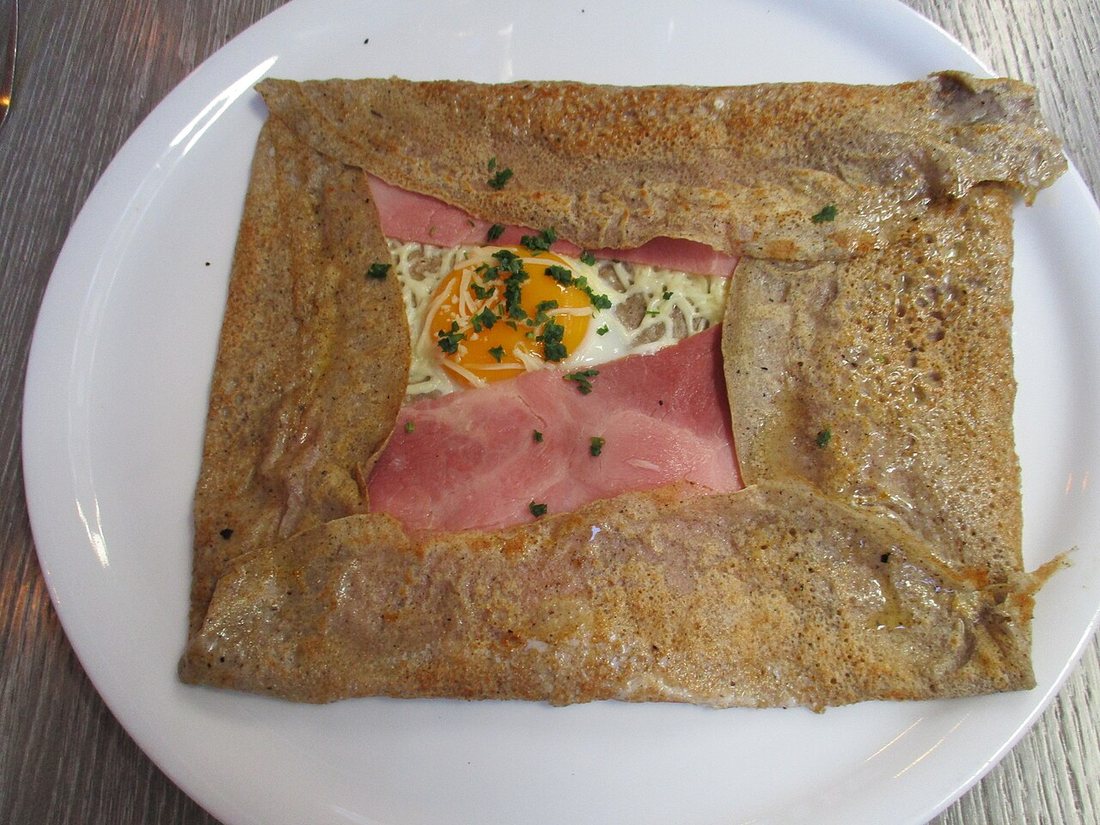 Une galette de sarrasin complète bretonne, garnie de jambon, d'œuf et de fromage, aux bords repliés en carré