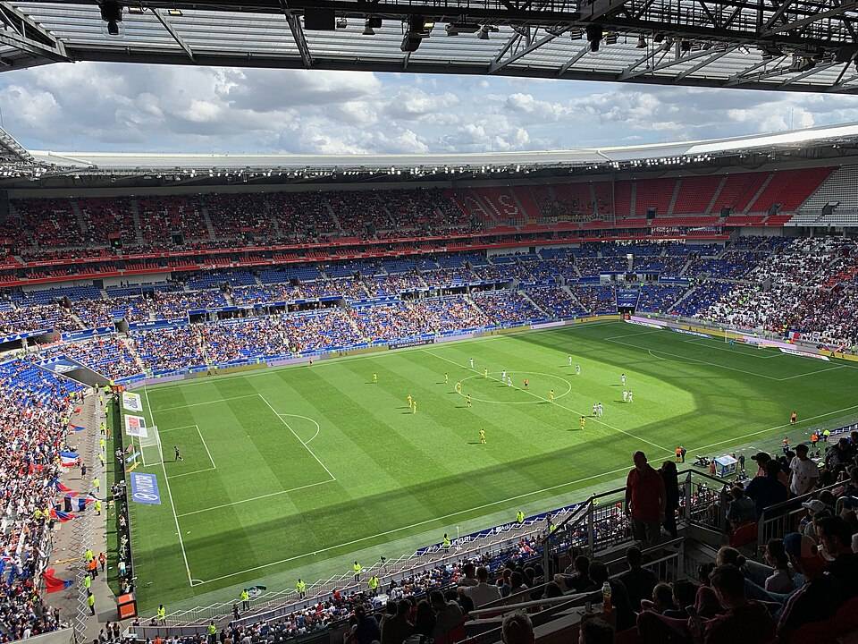 Le Groupama Stadium vu depuis les tribunes, pelouse éclairée et gradins garnis un soir de match