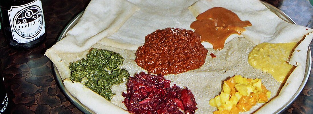 Un plateau éthiopien d'injera garni de plusieurs ragoûts de légumes et de légumineuses, servi sans viande