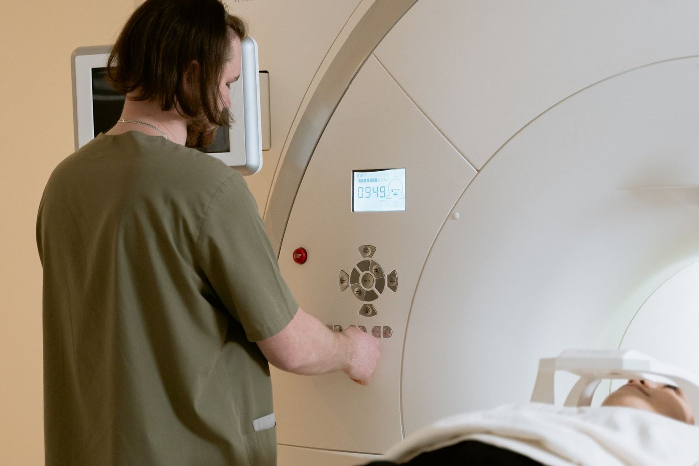 Manipulateur en radiologie devant la console de commande, un patient installé dans le tunnel de l'appareil d'IRM
