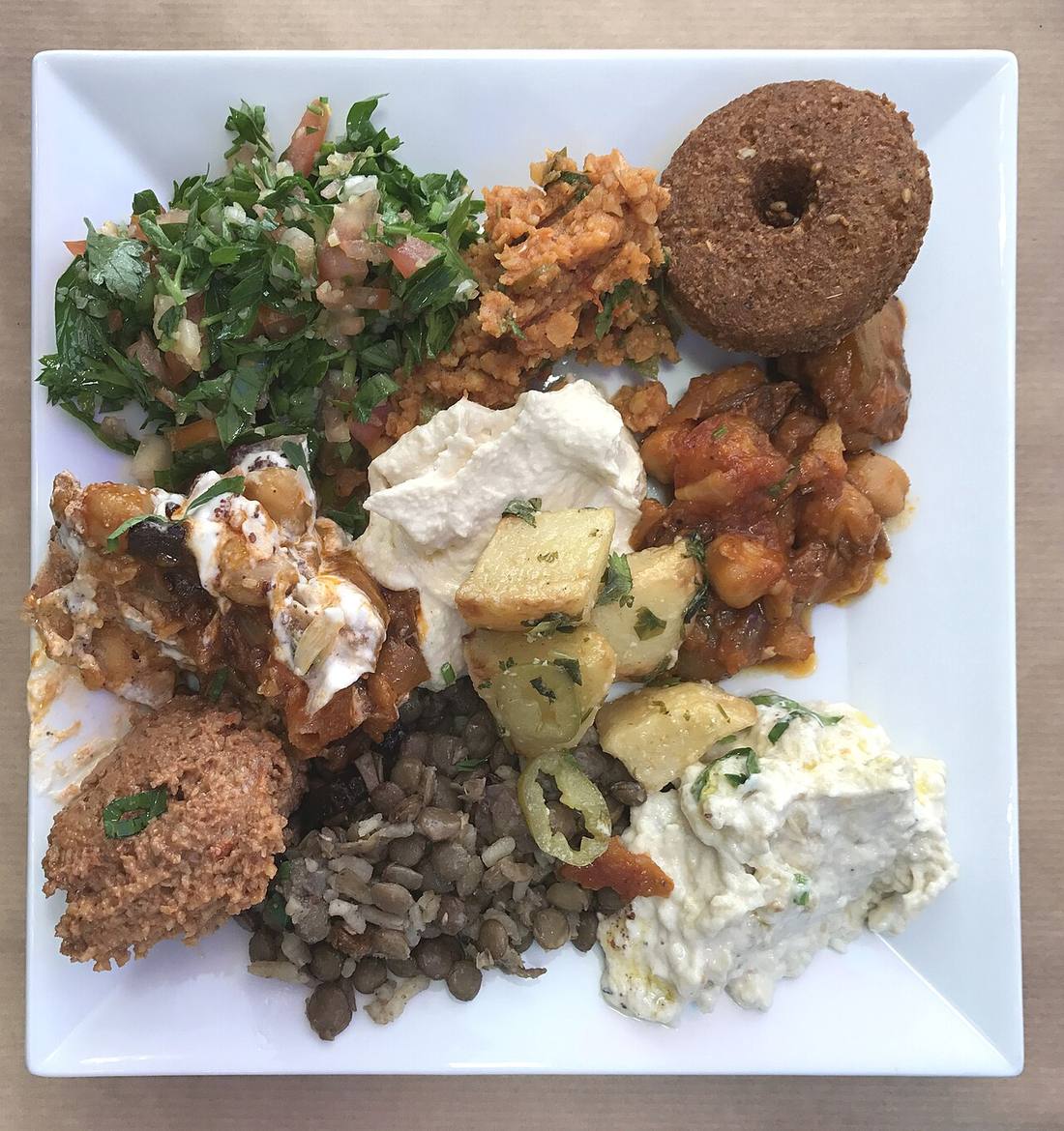 Un grand assortiment de mezzés libanais servi sur une table, avec purées, salades, feuilles de vigne et pain, dans un restaurant lyonnais