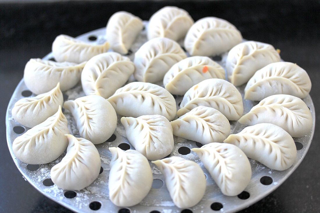 Des raviolis chinois jiaozi disposés dans une assiette, à la pâte de blé pliée et pincée à la main