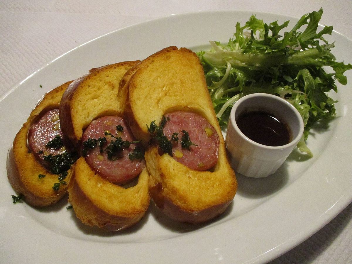 Tranche de saucisson pistaché en brioche, montrant les pistaches vertes dans la chair et la mie dorée autour