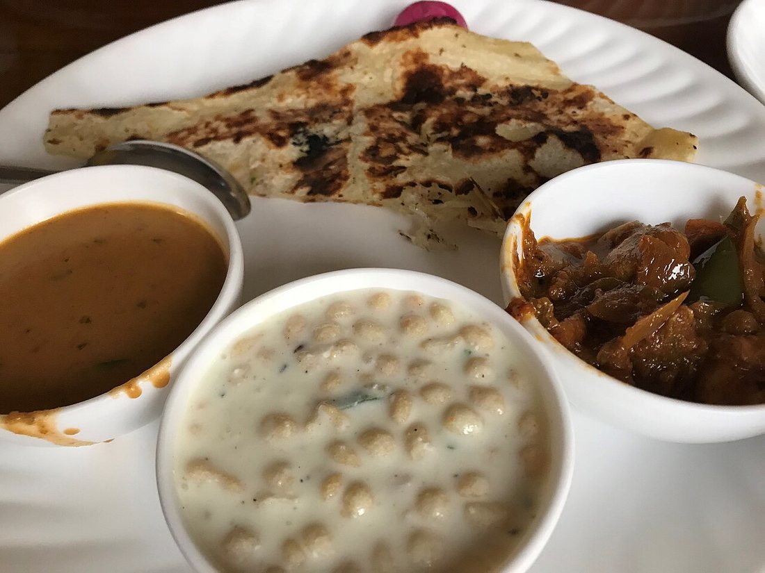 Un thali végétarien du nord de l'Inde servi sur un plateau métallique, avec plusieurs coupelles de préparations, riz et pain